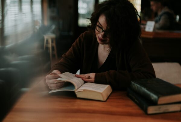 mujer leyendo la Biblia en una mesa con otros libros