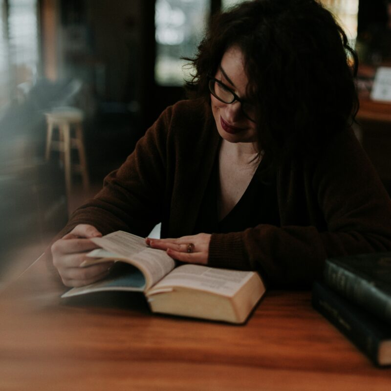 woman reading Bible at table with other books