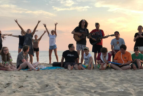 high school students worship on the beach
